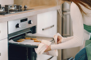 Young woman taking baked cookies out of the oven which inspired a home cookie business