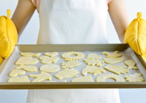 Woman holding sheet of cut out cookie dough shapes that inspired a home cookie business