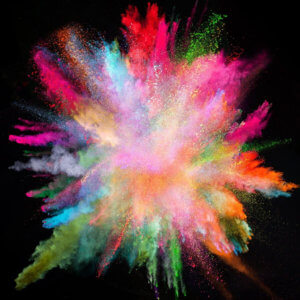 Explosion of brightly colored powder on a black background, to represent feeling overwhelmed when starting a cookie business