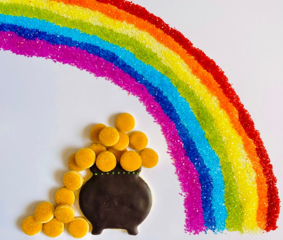 Platter of black pot overflowing with gold decorated cookies, and a rainbow made of sparkly colored sugar