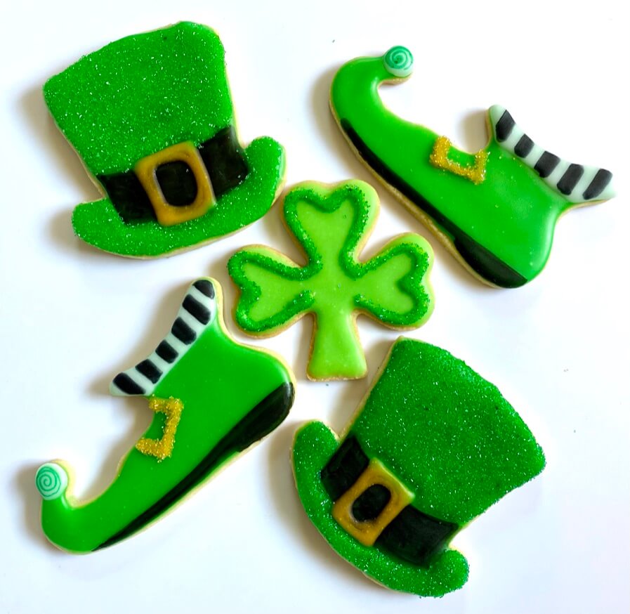 Platter of Saint Patrick's Day cookies, decorated as green leprechaun hats and shoes, with a shamrock